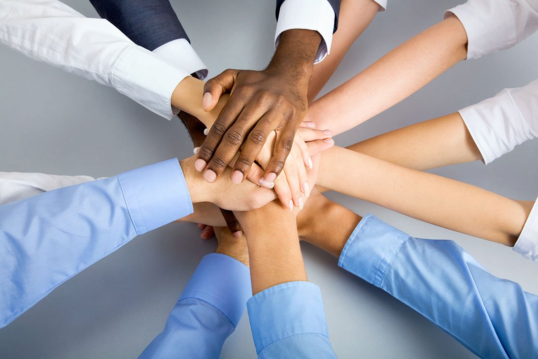 A team of professionals stacking hands together — VANZA Marketing teamwork